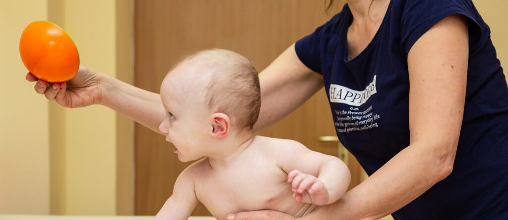 Fizjoterapia pediatryczna - niemowlę wykonujące ćwiczenia na stole terapeutycznym