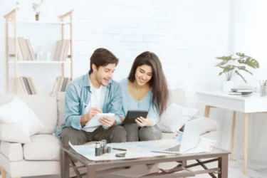 Para na kanapie w salonie przegląda online ofertę INTER Polska - prywatne ubezpieczenie zdrowotne INTER Vision.